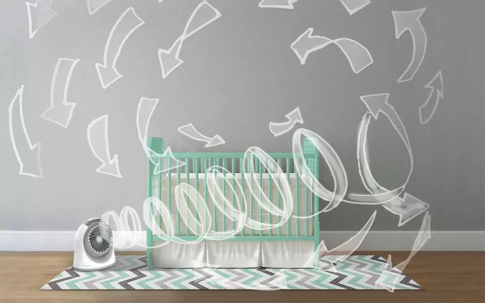 Breesi Circulation Banner Breesi Small Nursery Air Circulator in a nursery by a crib. Pale white arrows are drawn throughout the room to indicate circulation pattern