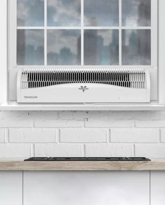 White Transom window air circulator in a window with raindrops on the window panes