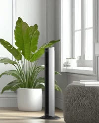 Lifestyle image of OZI42DC tower fan by a white wall, green plant and a window.