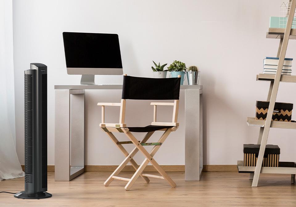 960x670 OZI42 Lifestyle Lifestyle of OZI42 Tower Circulator next to a chair and a desk with a mac desktop on it