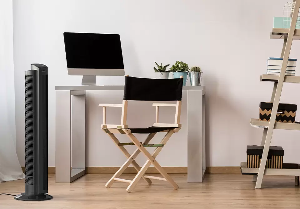 960x670 OZI42 Lifestyle Lifestyle of OZI42 Tower Circulator next to a chair and a desk with a mac desktop on it