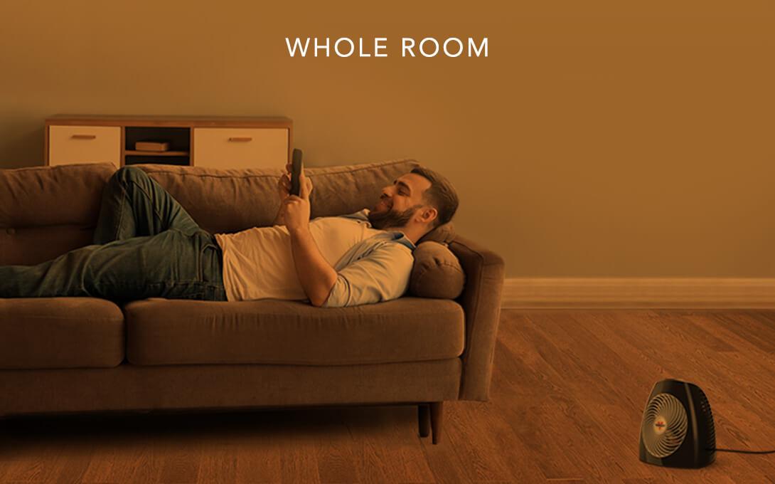 MVH Whole Room Man laying on a couch with the MVH heater on the floor. There is an orange overlay to indicate whole room heat.