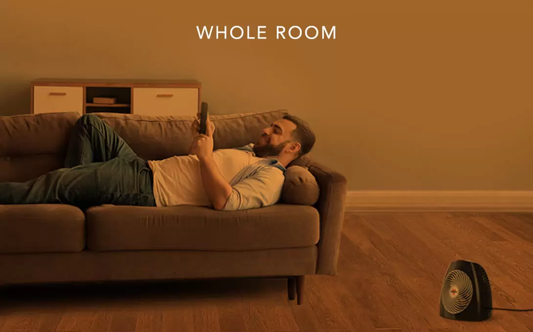 MVH Whole Room Man laying on a couch with the MVH heater on the floor. There is an orange overlay to indicate whole room heat.