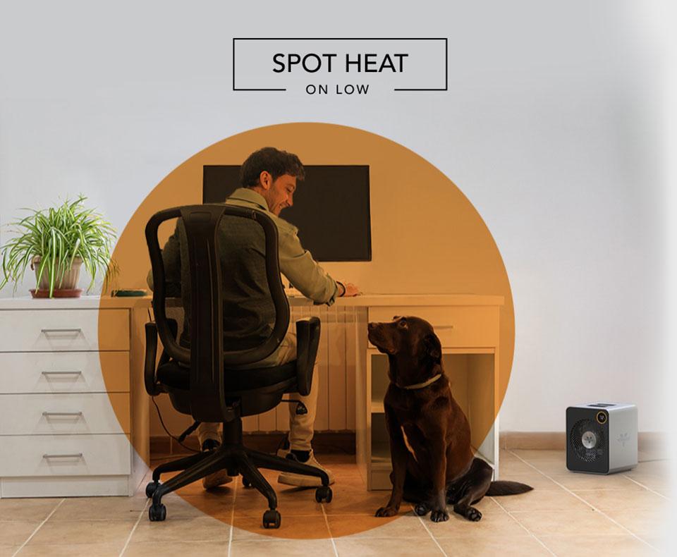 VMHi600 Spot Heat Man sitting at desk with smiling at his dog. A VMHi600 heater is on the floor nearby. There is an orange circle overlay on him to indicate spot heat on low.