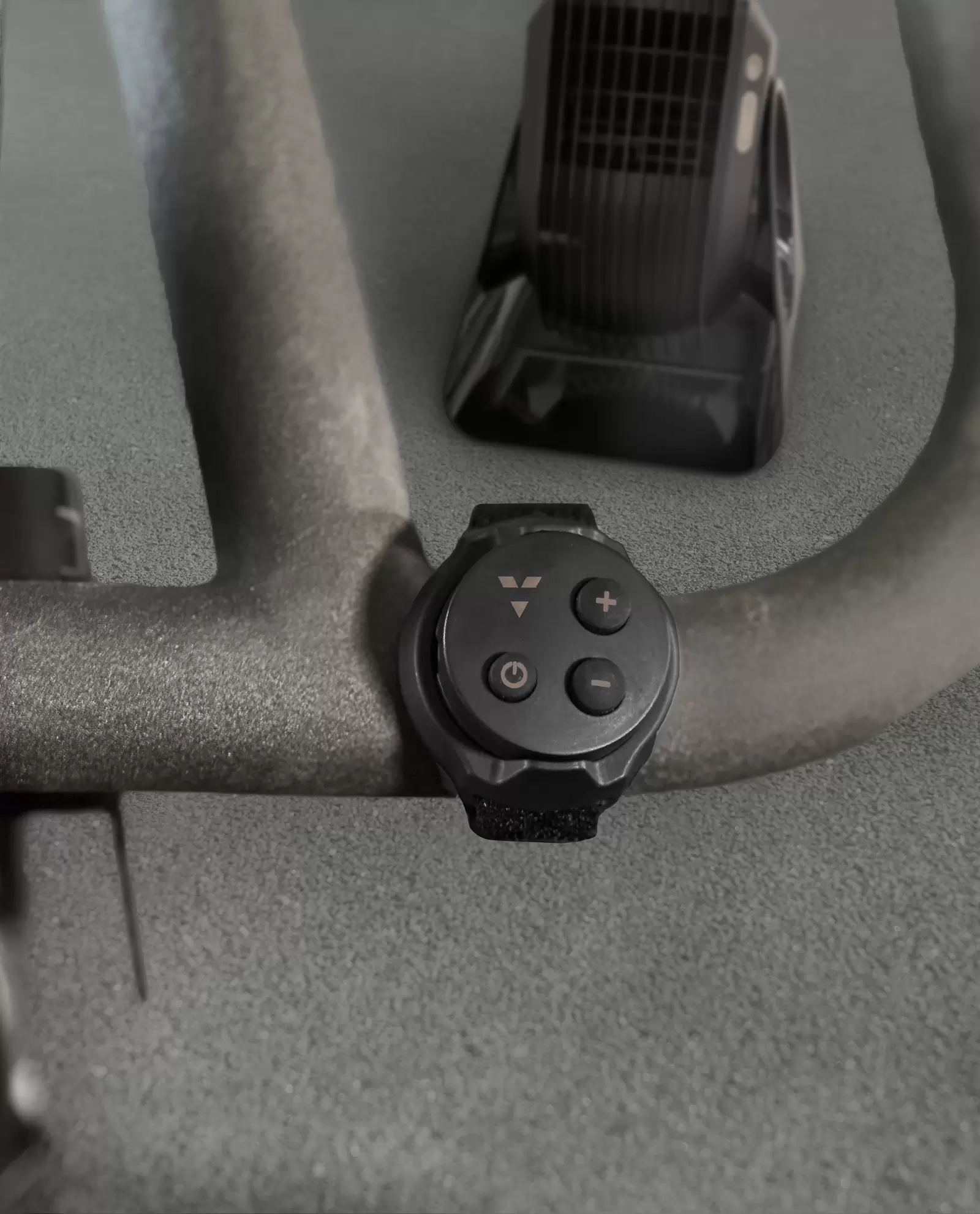 Vornado FLY MAX Remote attached to a stationary bike handle in front of a Vornado Fly Max