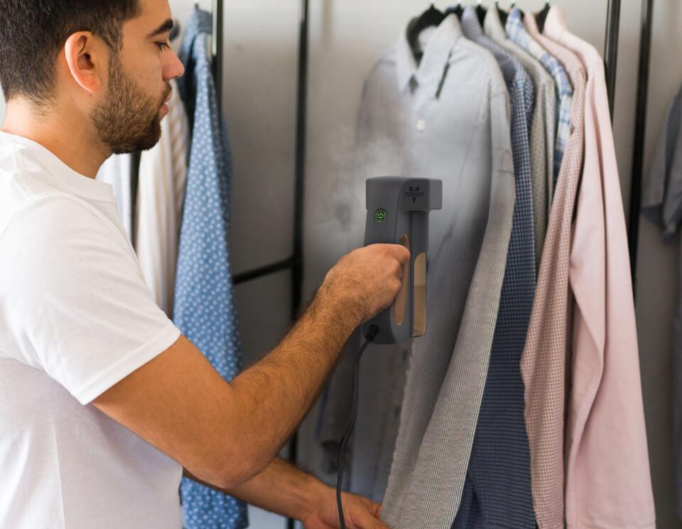 Express in Use Man using the express handheld garment steamer to steam a gray long-sleeved shirt