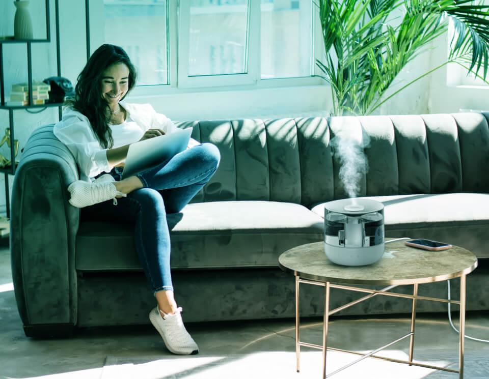 Mistic 4 Humidity Whole Room Woman on laptop in living room with Mistic 4 humidifying the room on her coffee table