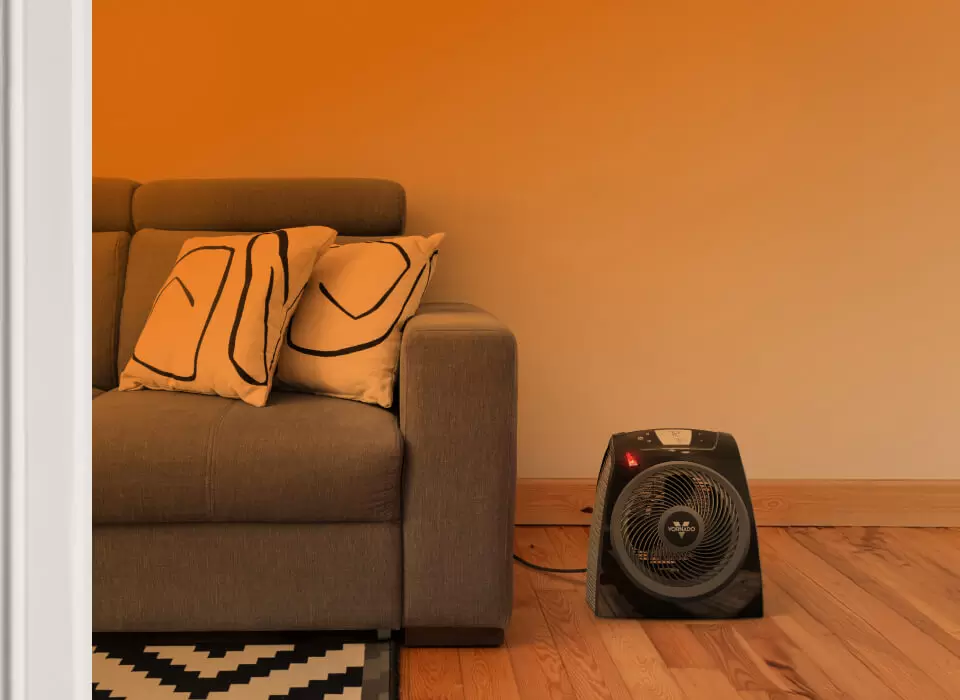 TAVH10+ Whole Room Part of a living room seen through an open door with an orange gradient to show whole room heat circulation. TAVH10+ is on the floor near a couch.