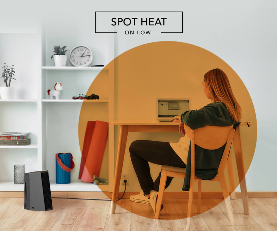 Woman sitting at desk with the Rise 12H heater on the floor. There is an orange circle overlay on her to indicate spot heat on low.